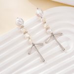 Silver-tone pearl chandelier earrings laid on a white surface