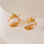 Baroque pearl studs with wheat-inspired gold-tone framing on white display