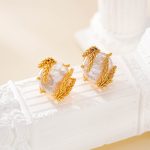 Wheat-wrapped baroque pearl studs resting on a white textured display