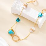 Close-up of turquoise stones, wire-wrapped pearl and gold-tone ring on necklace
