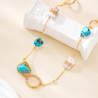 Close-up of turquoise stones, wire-wrapped pearl and gold-tone ring on necklace