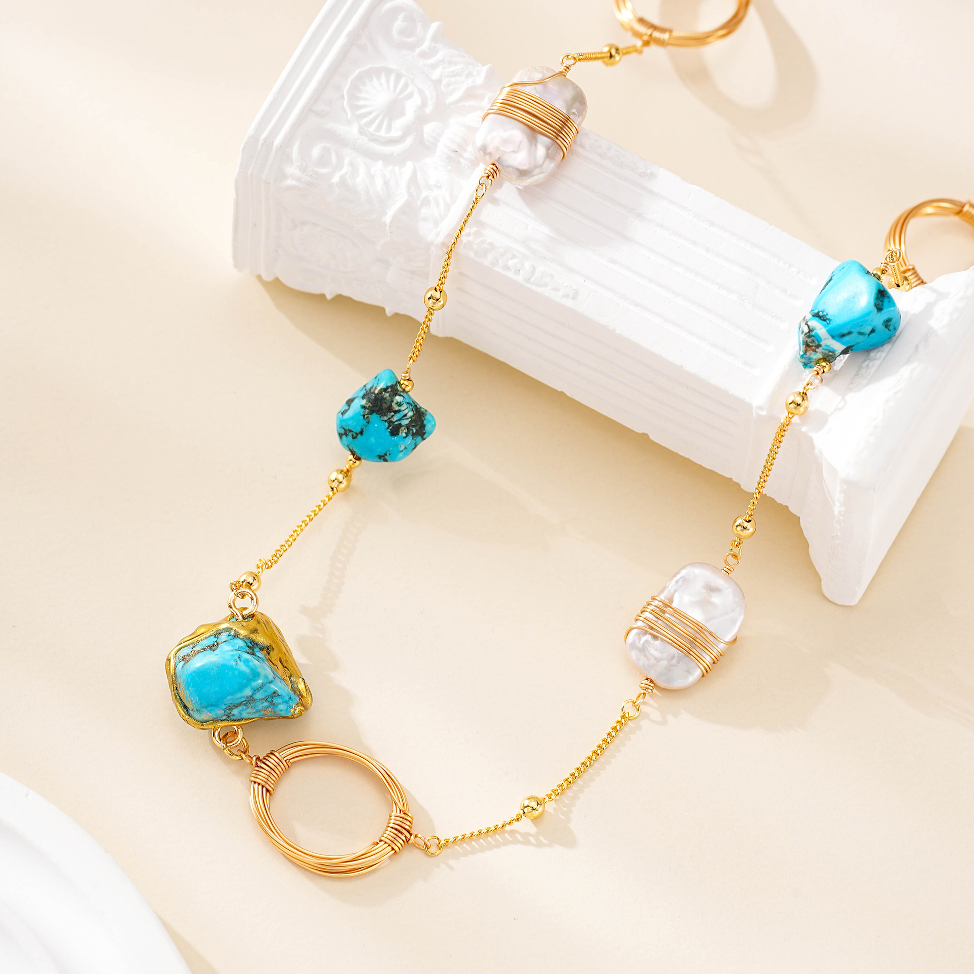 Close-up of turquoise stones, wire-wrapped pearl and gold-tone ring on necklace