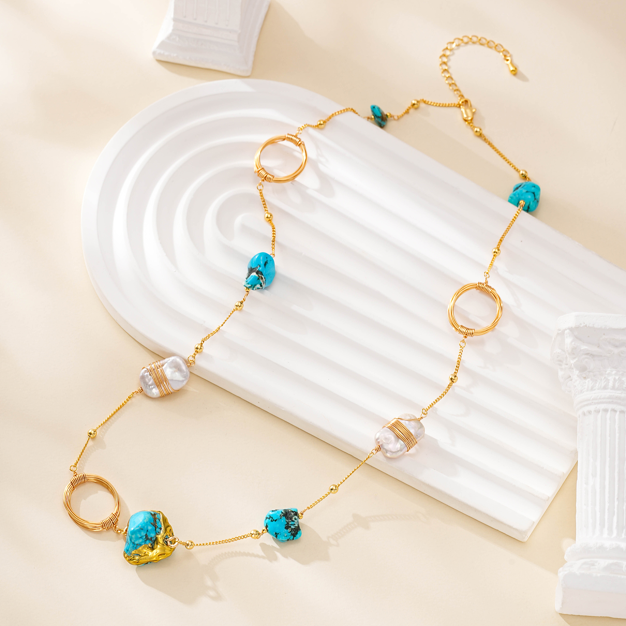 Turquoise and pearl necklace laid across a white curved display