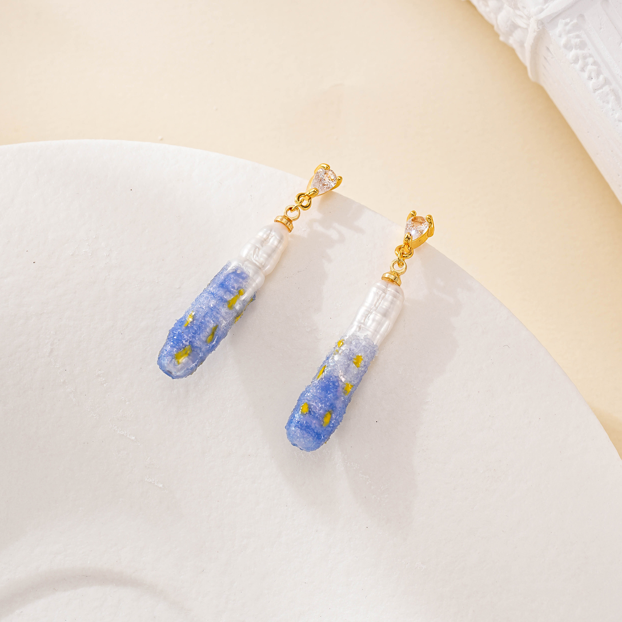Close-up of painted blue pearl drop earrings with stud posts
