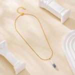 Painted pearl pendant necklace laid in a loop on a cream surface