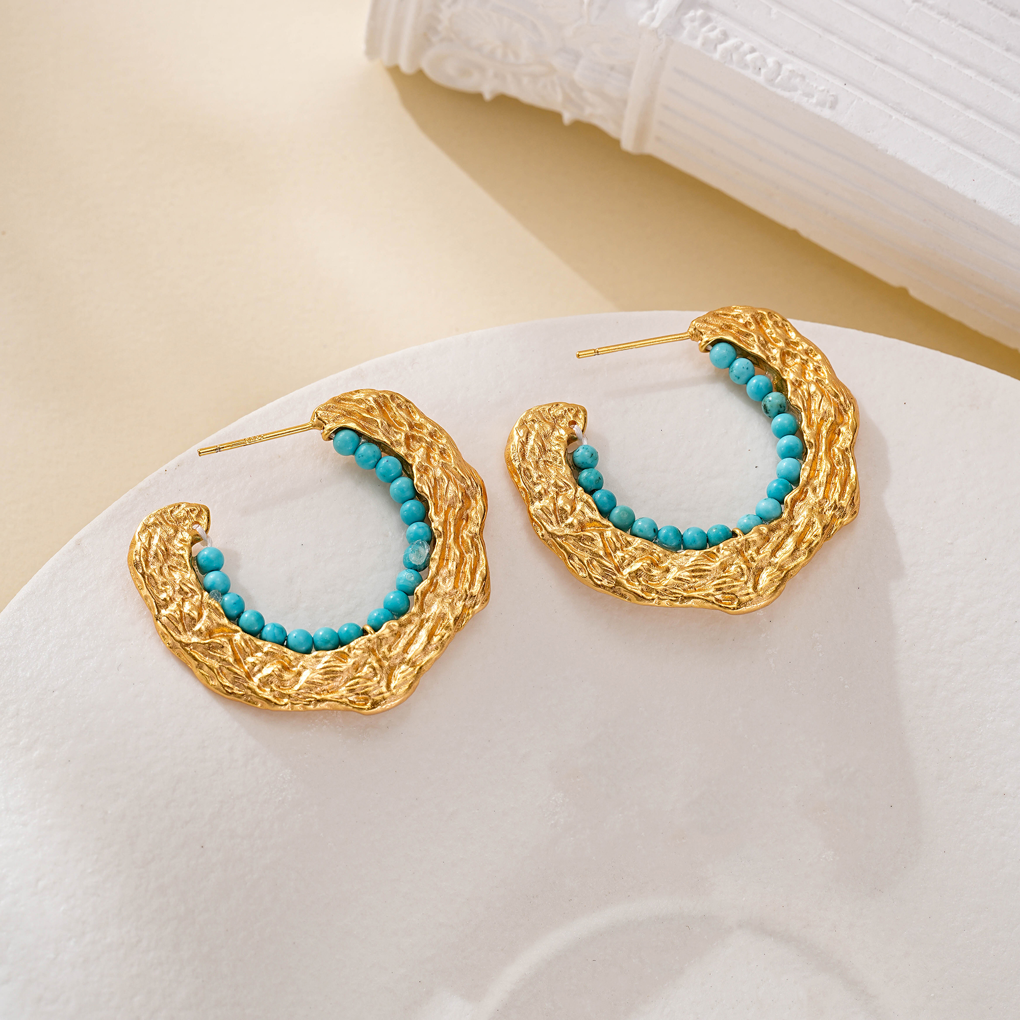 Close-up of turquoise bead trim inside textured C-hoop earrings