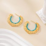 Open C-hoop earrings with turquoise beads on a cream background