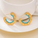 Turquoise-lined C-hoop earrings leaning against a white display