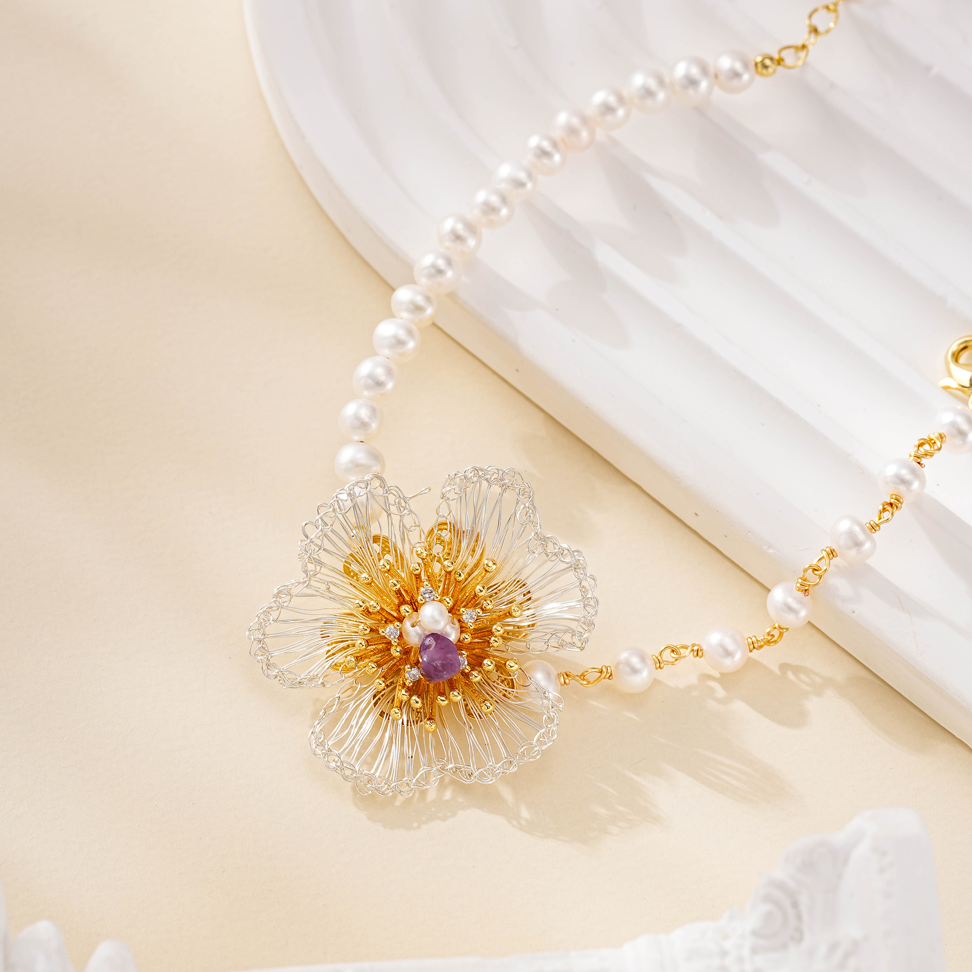 Close-up of amethyst-centered wire flower on a pearl bracelet