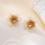 Pair of amethyst and pearl floral stud earrings on a cream surface