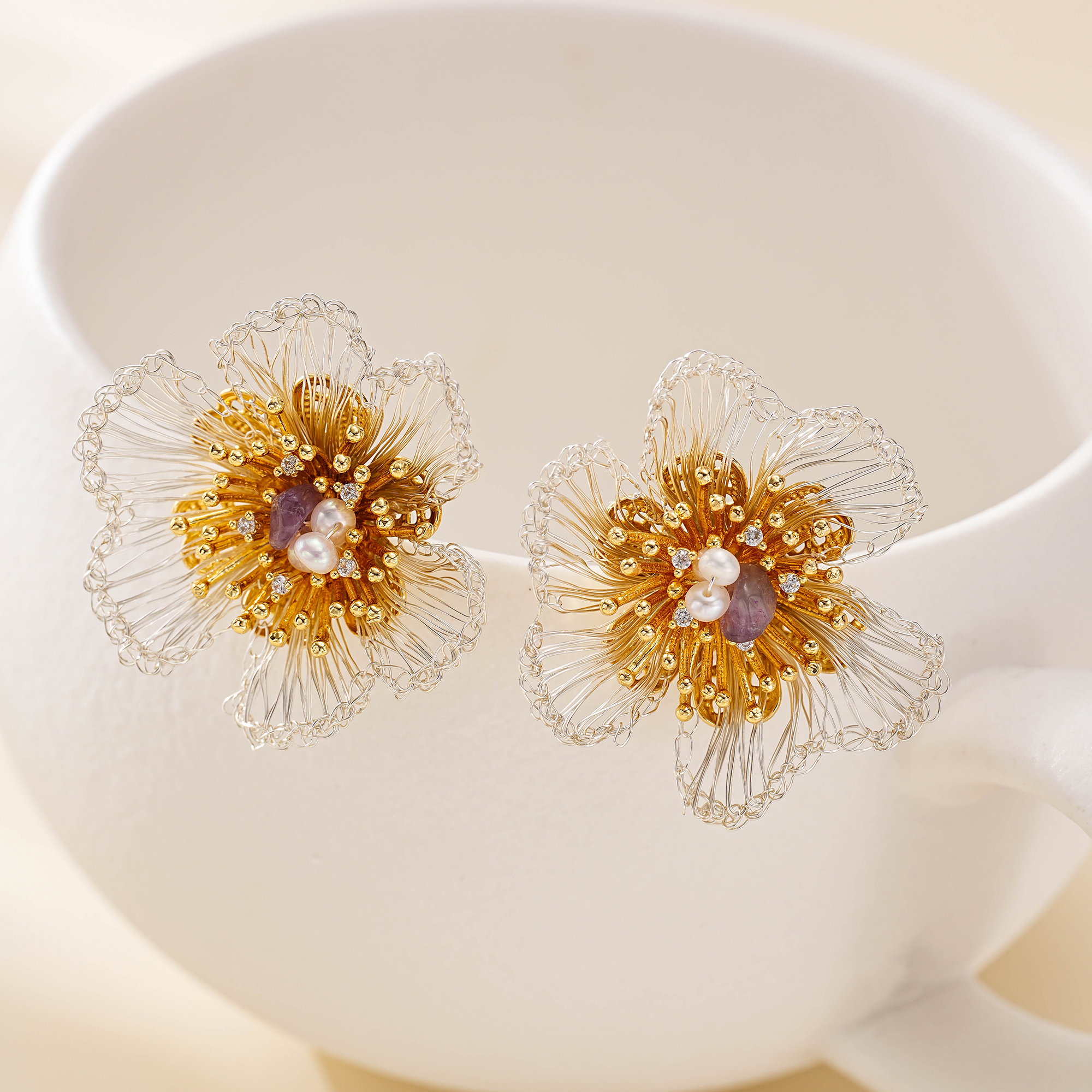 Floral stud earrings with silver-tone wire petals on a white display