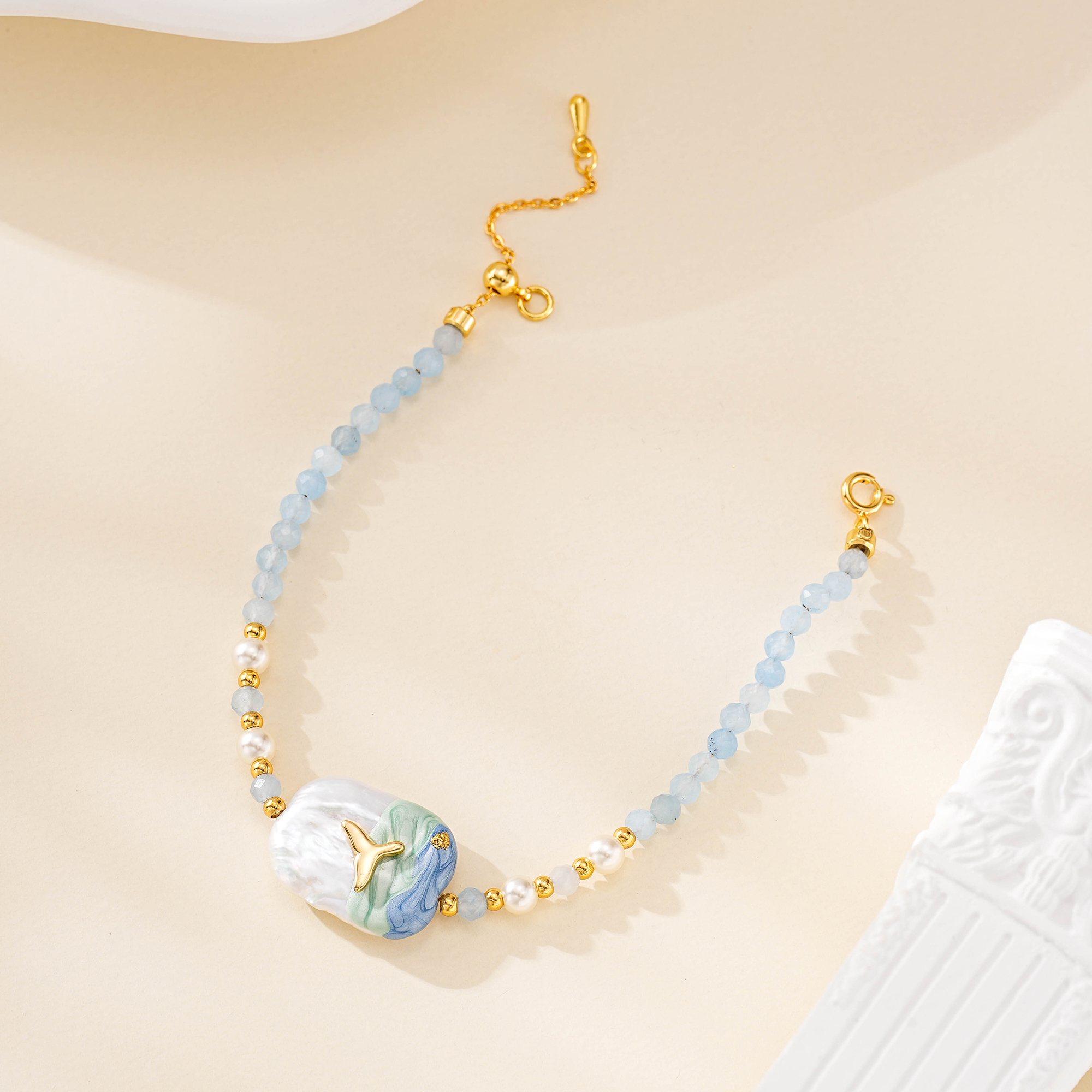 Full view of blue bead bracelet with painted pearl charm