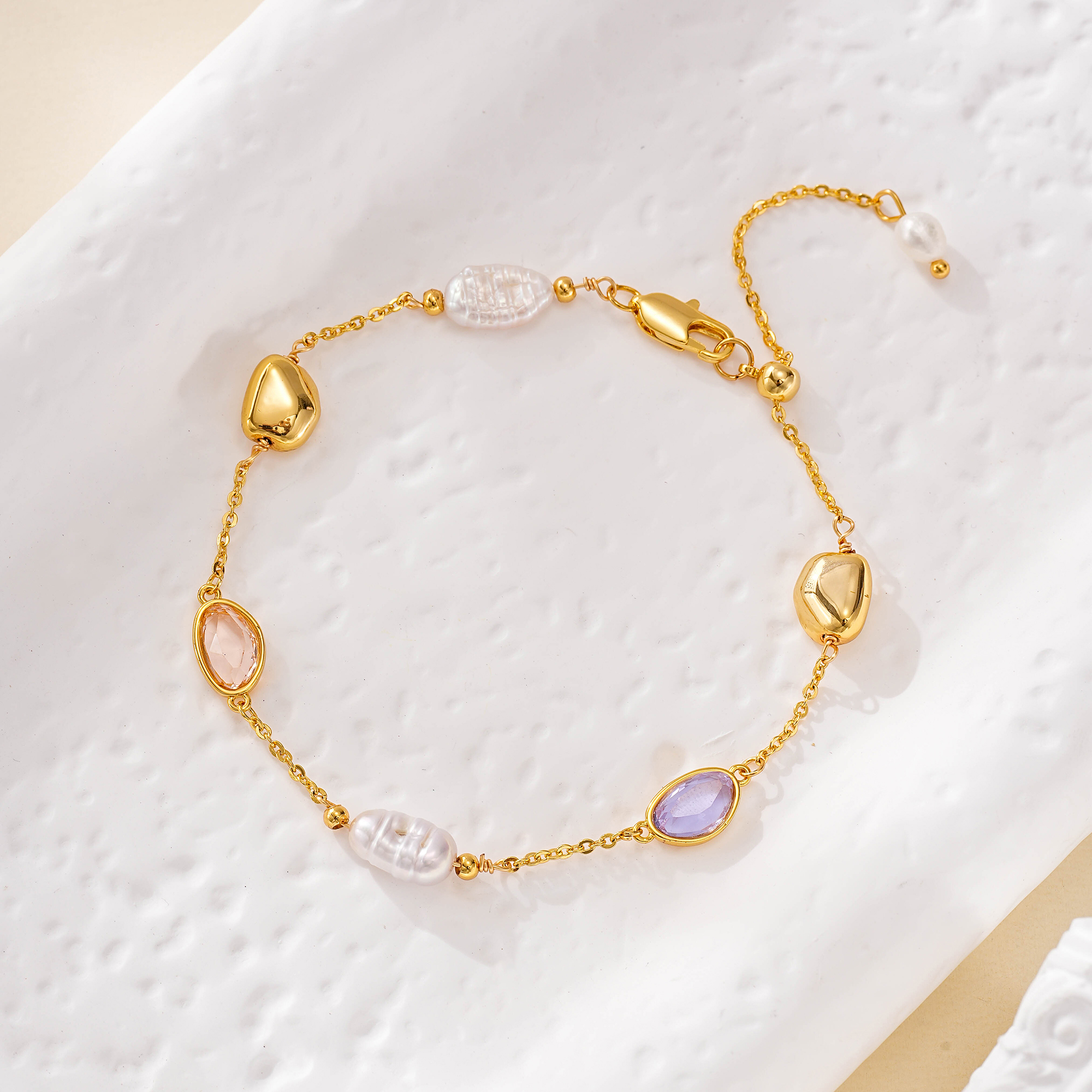 Pastel gemstone and pearl chain bracelet on white fabric