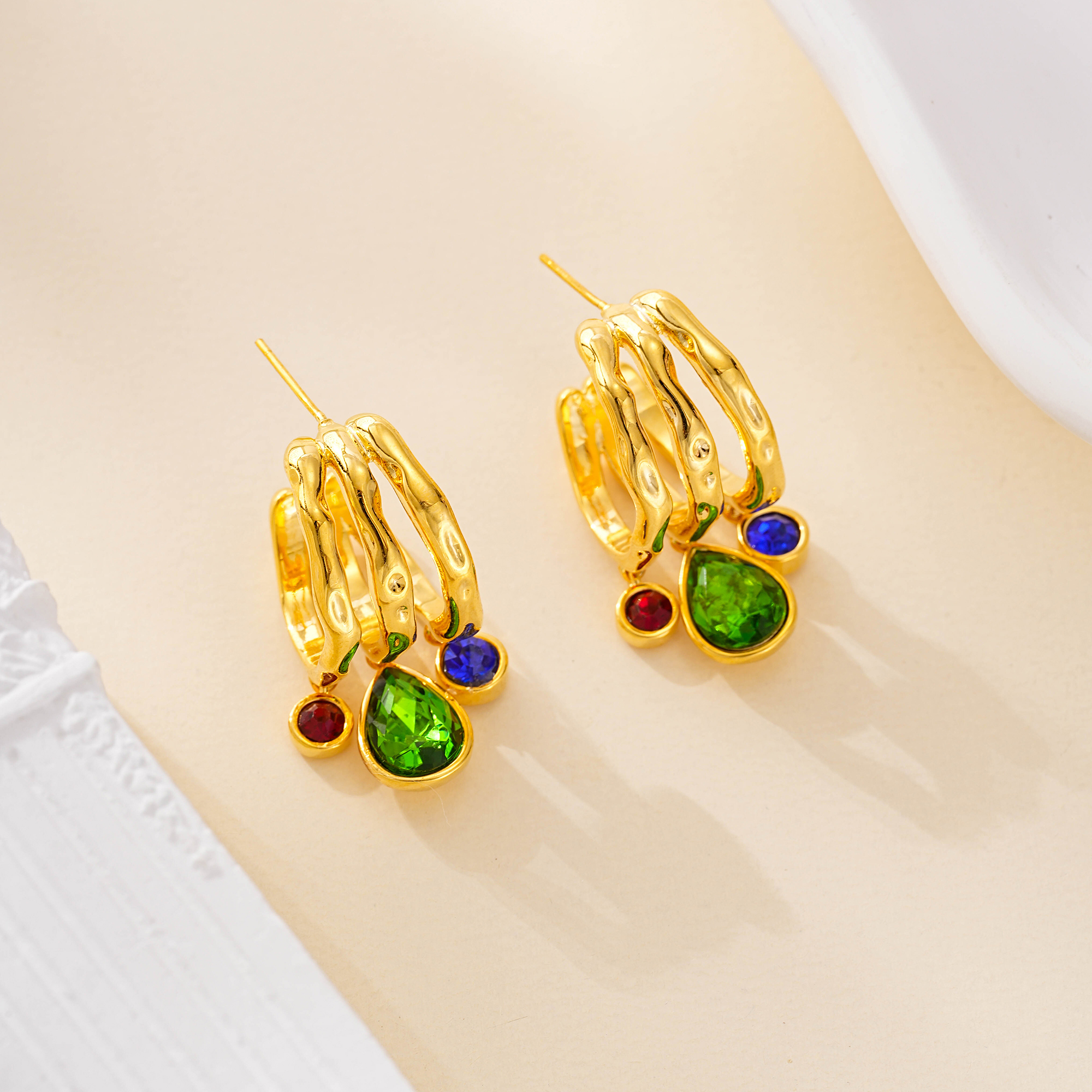 Triple gold-tone hoop earrings with green blue and red stones