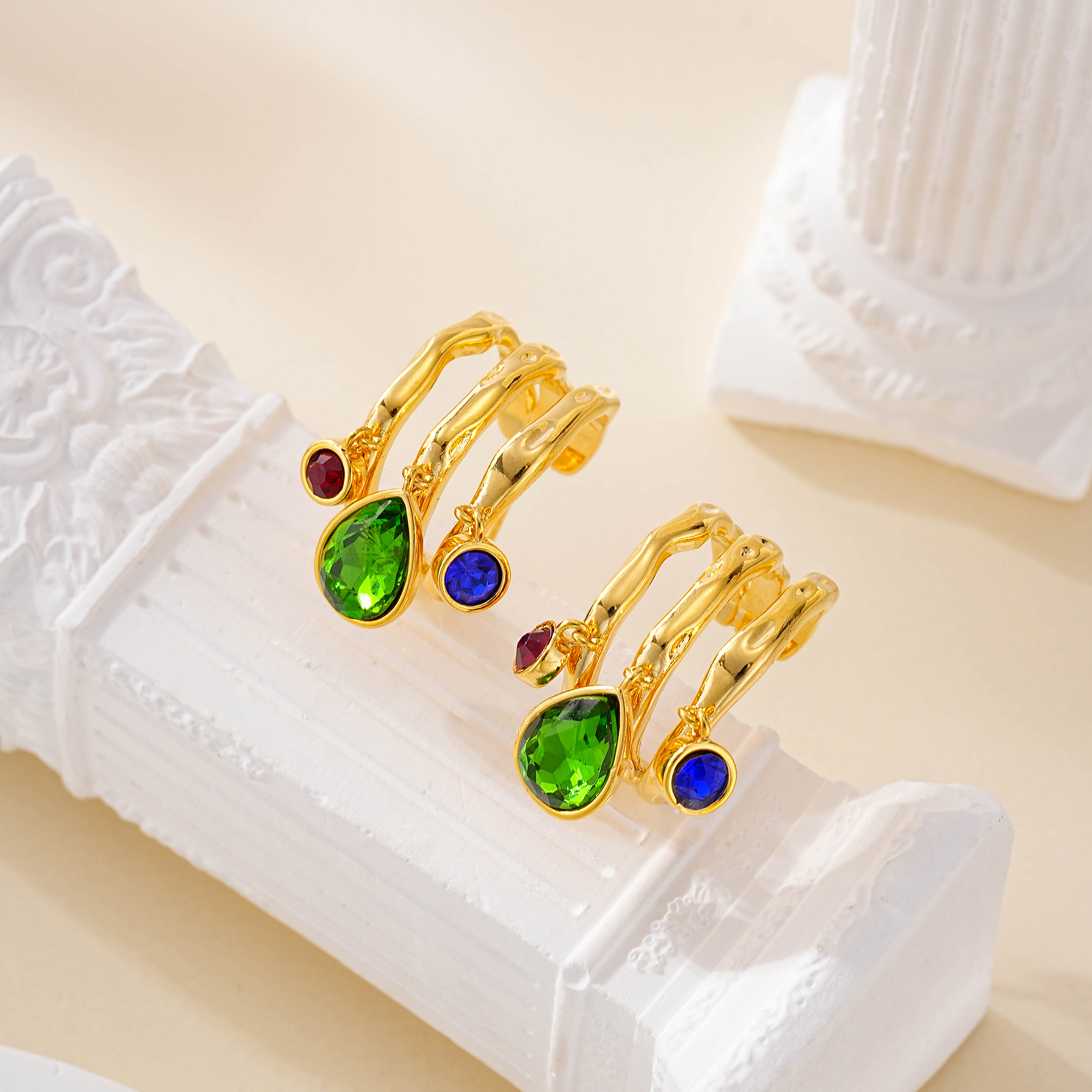 Close-up of multicolor stone charms on layered hoop earrings
