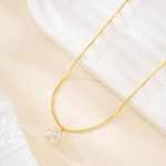 Long gold-tone necklace with a faceted clear crystal pendant