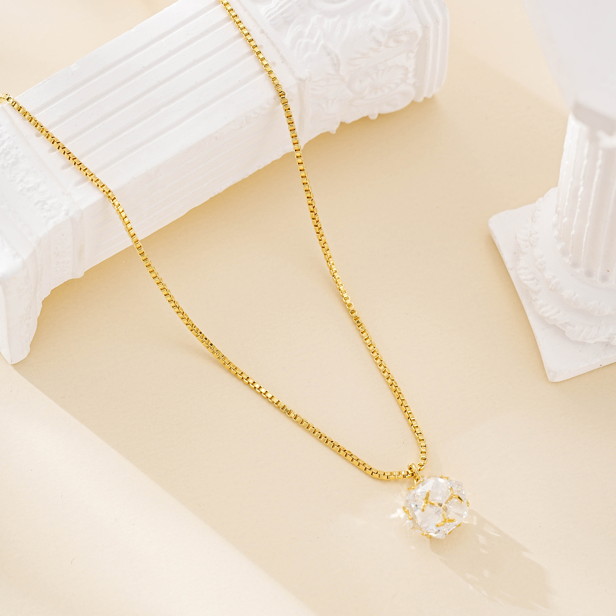 Long crystal pendant necklace draped beside white columns