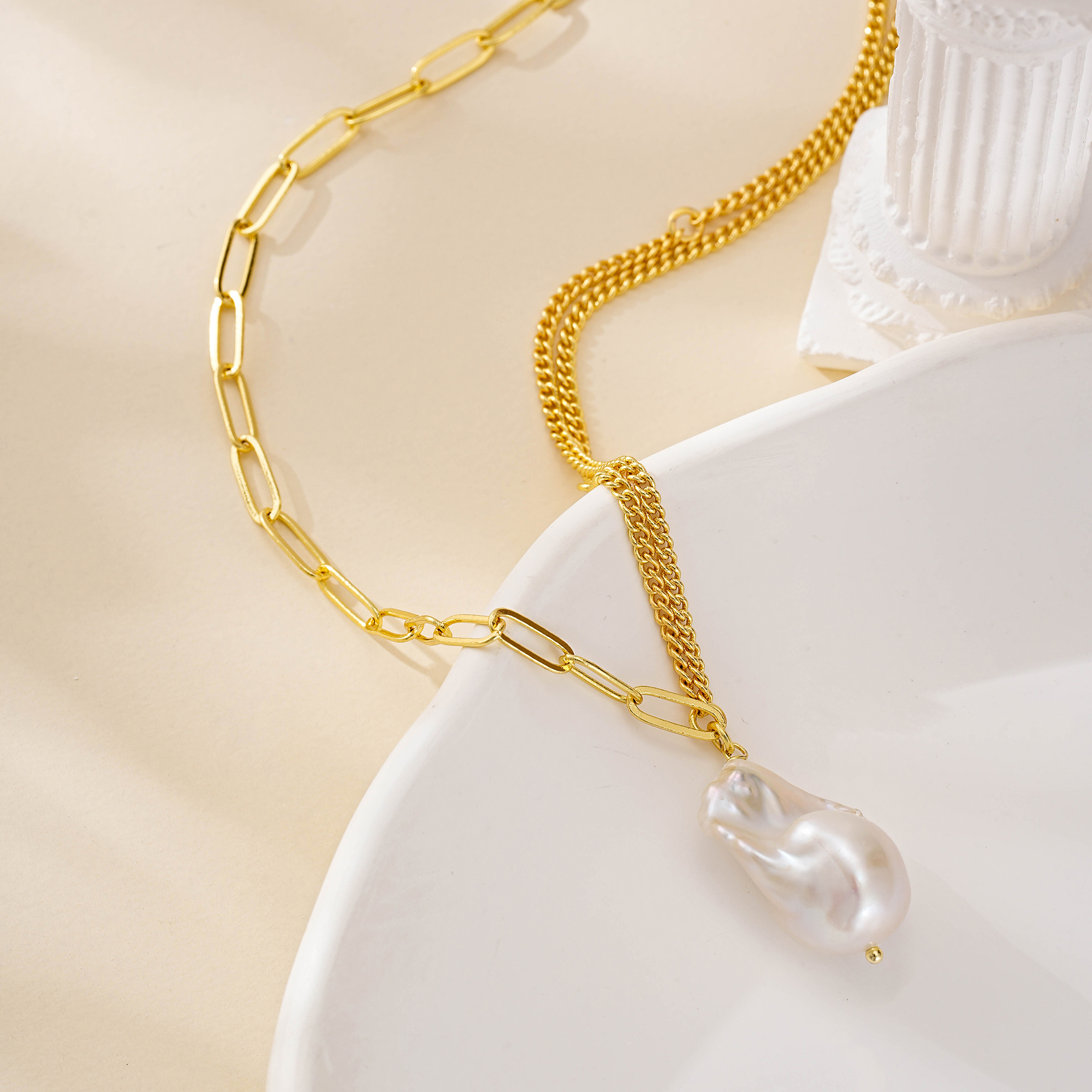Close view of the baroque pearl hanging between contrasting chains