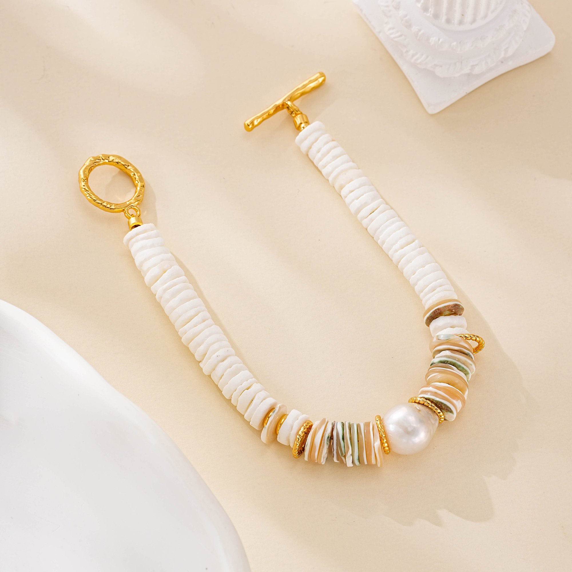 Coastal pearl and shell bracelet laid out in a circle