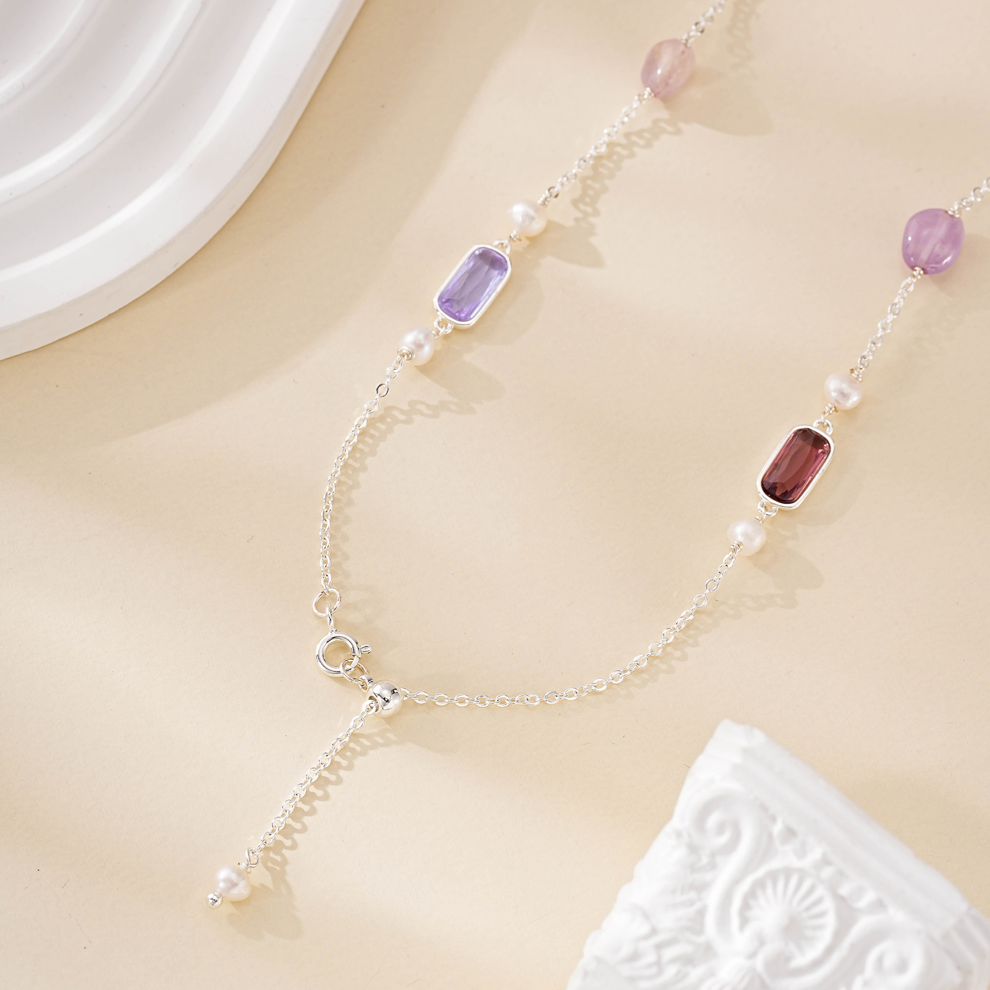 Close-up of purple gemstone and pearl accents on silver-tone necklace