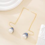 Gold-tone earring threads and baroque pearl drops laid out