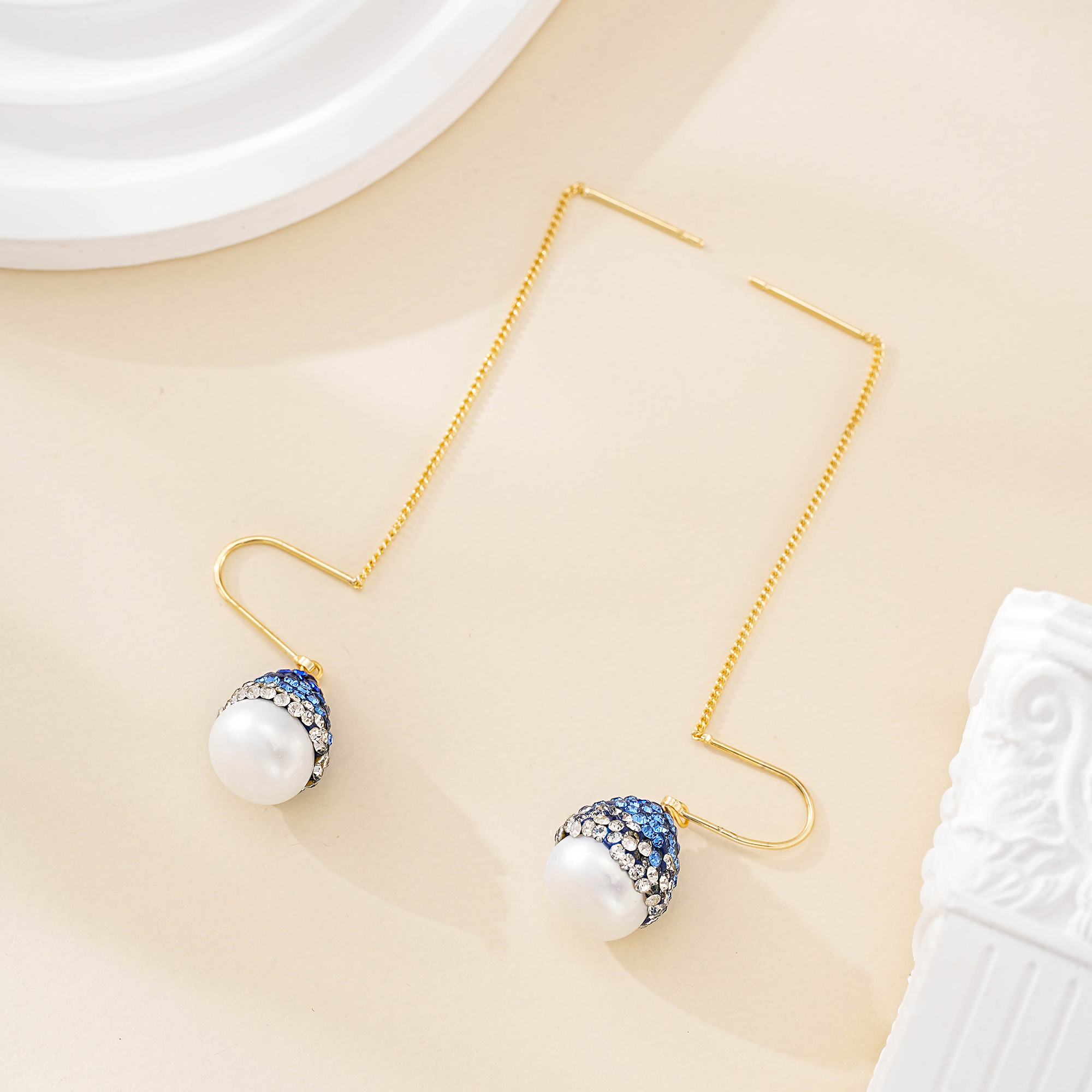 Gold-tone earring threads and baroque pearl drops laid out
