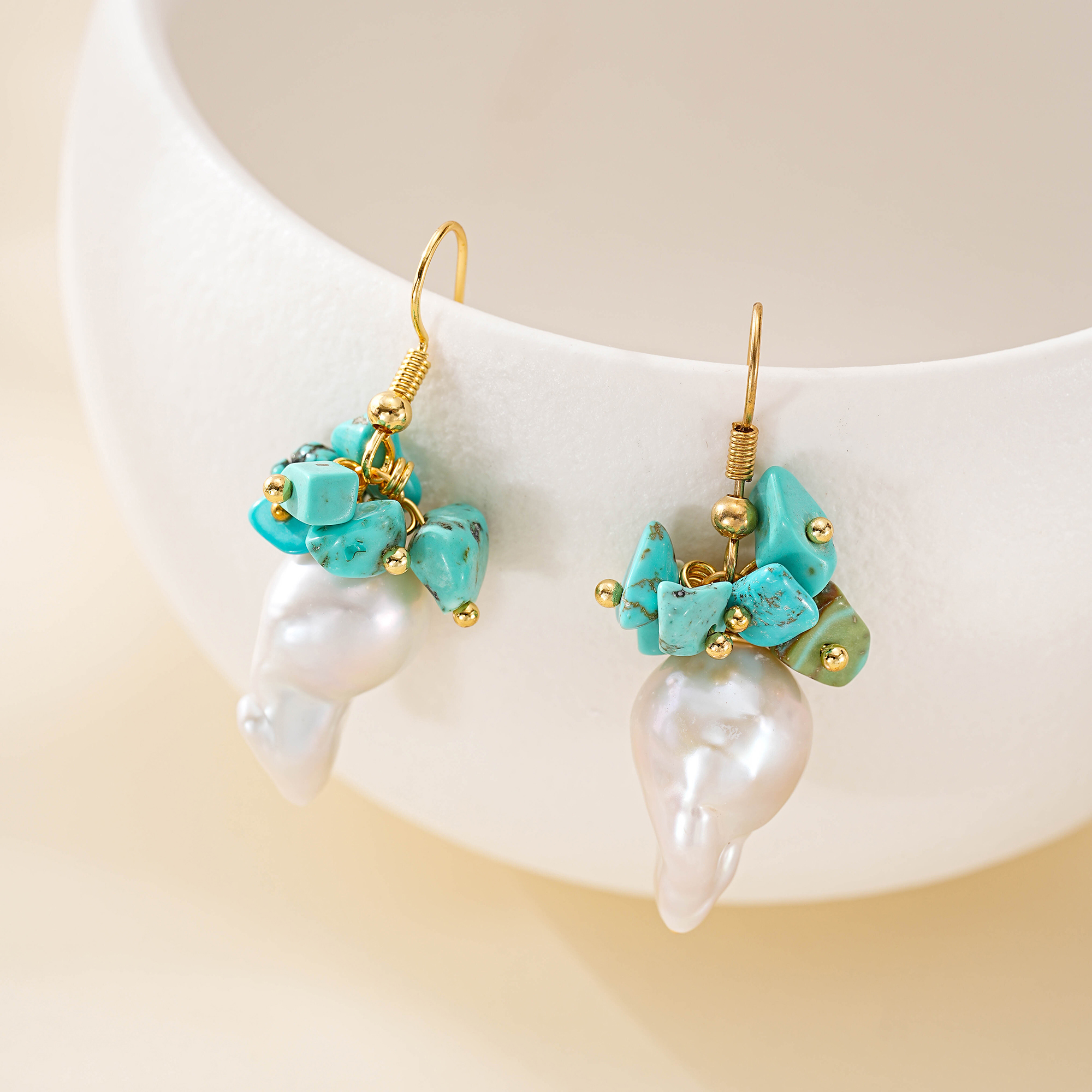 Pair of turquoise and baroque pearl drop earrings on a light backdrop