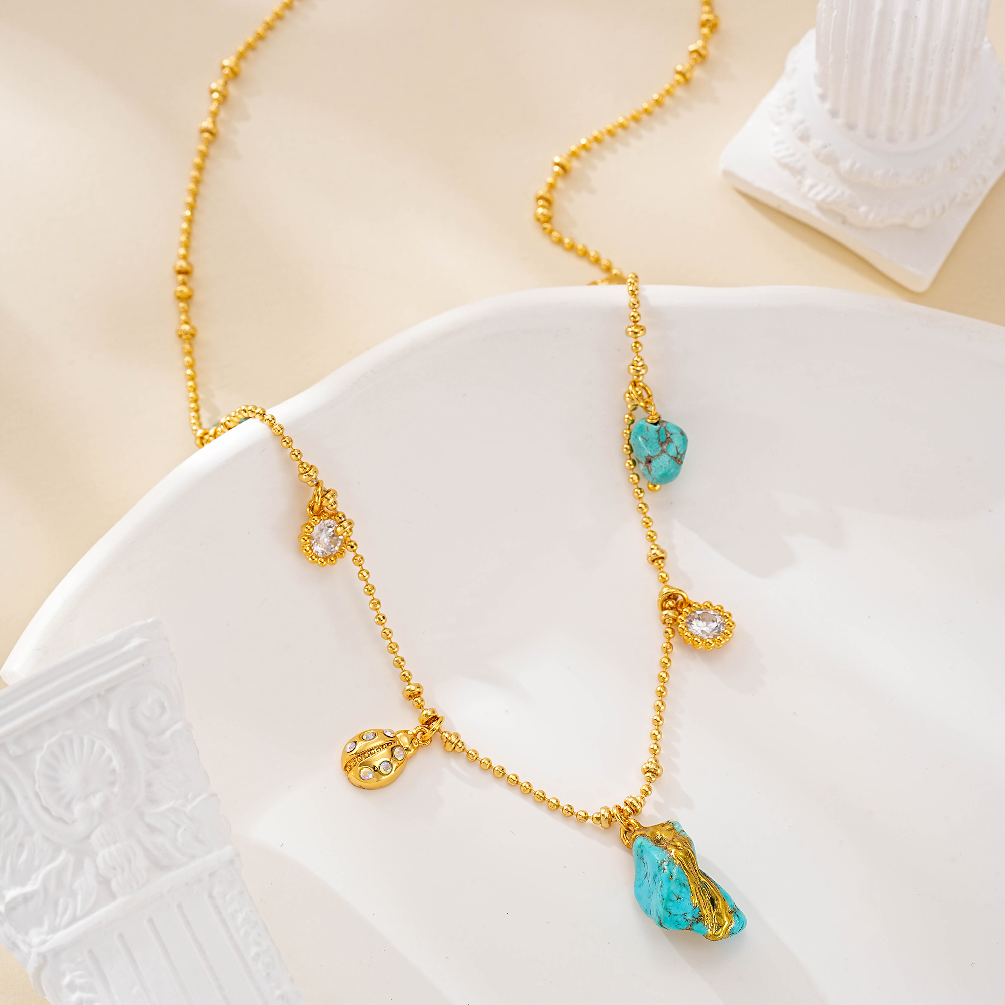 Detail of small turquoise charms along the gold-tone chain