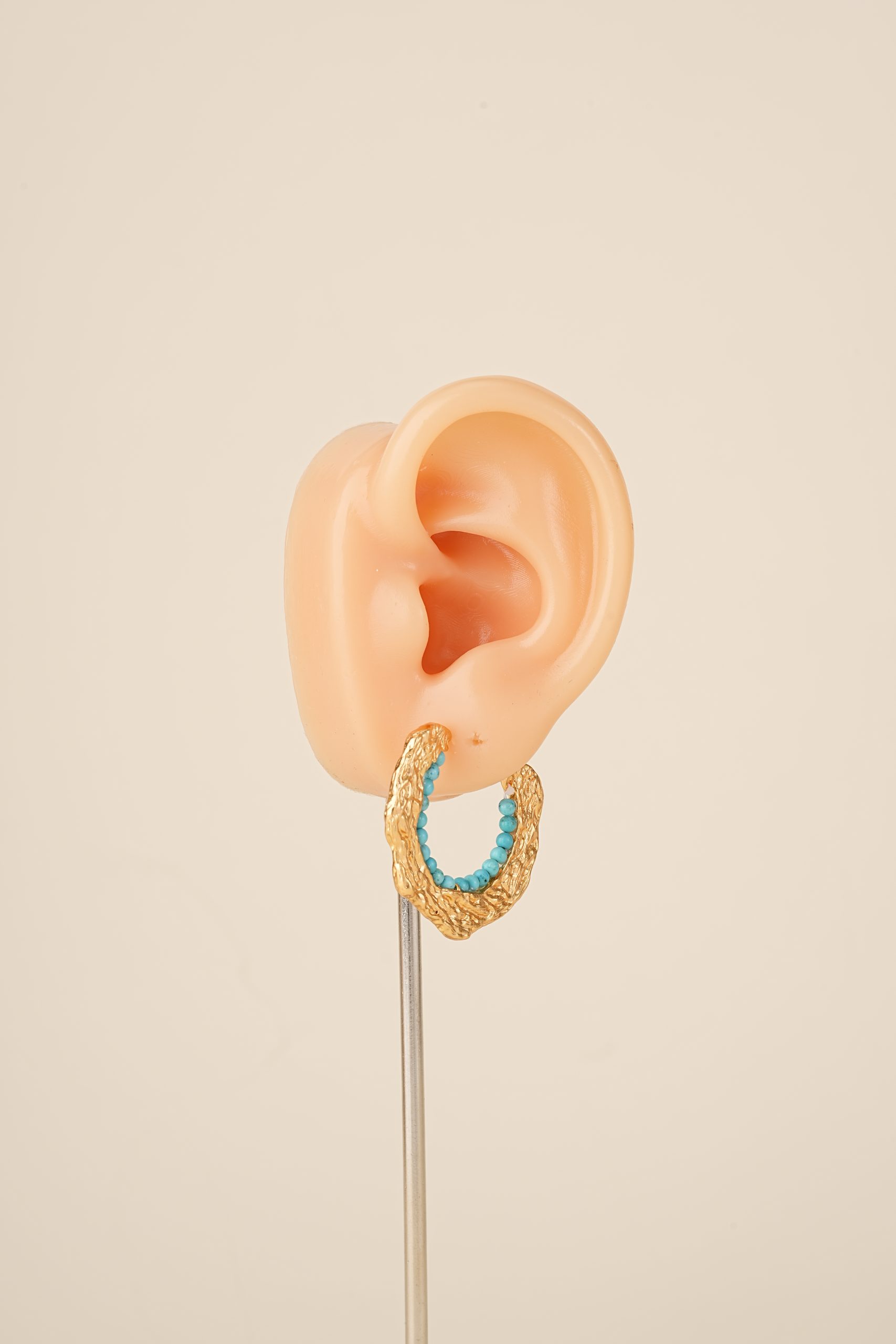 Turquoise bead C-hoop earring on an ear display