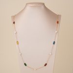 Long multicolor gemstone and pearl necklace displayed on a bust
