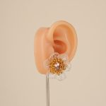 Amethyst and pearl floral stud earring on an ear display