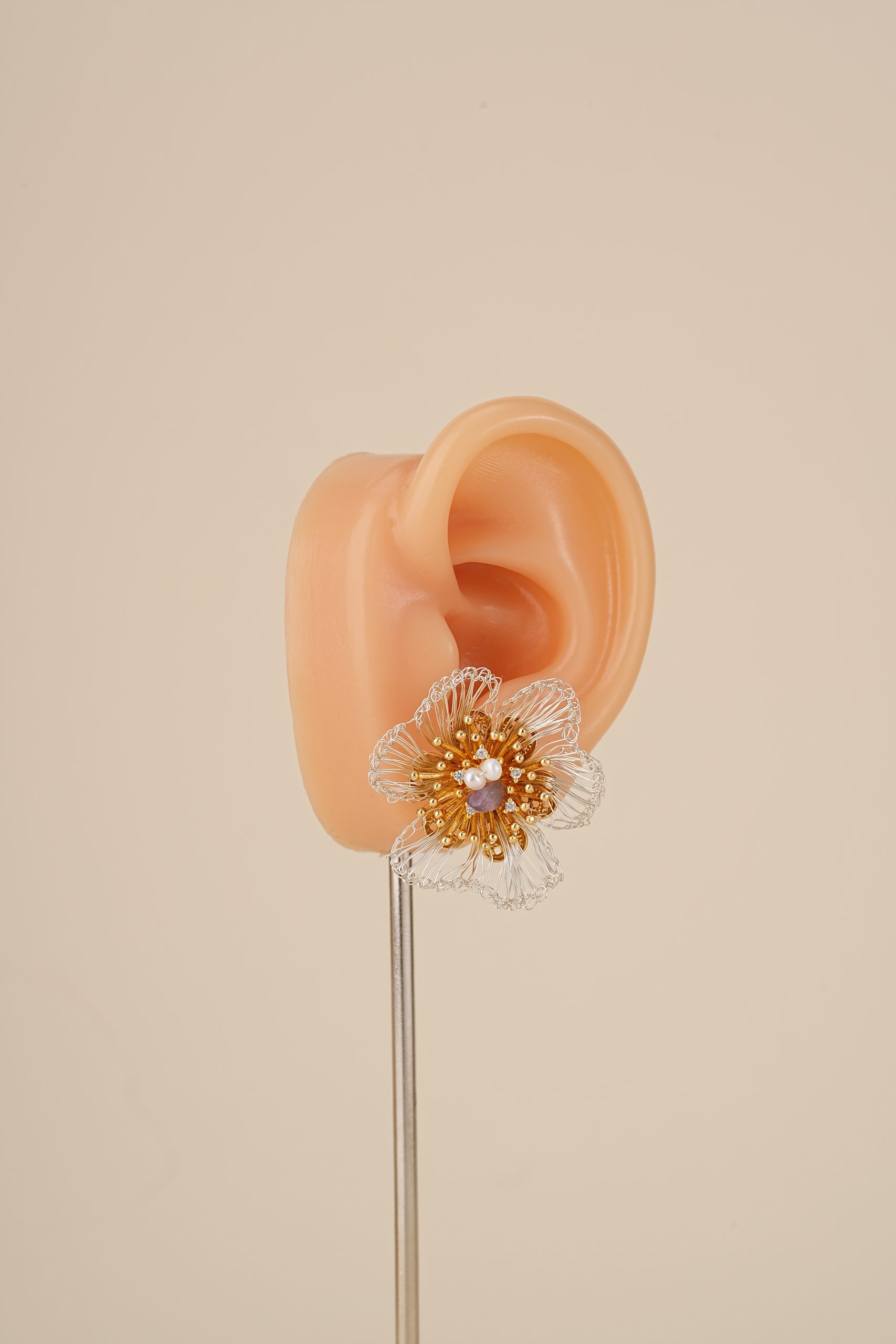 Amethyst and pearl floral stud earring on an ear display