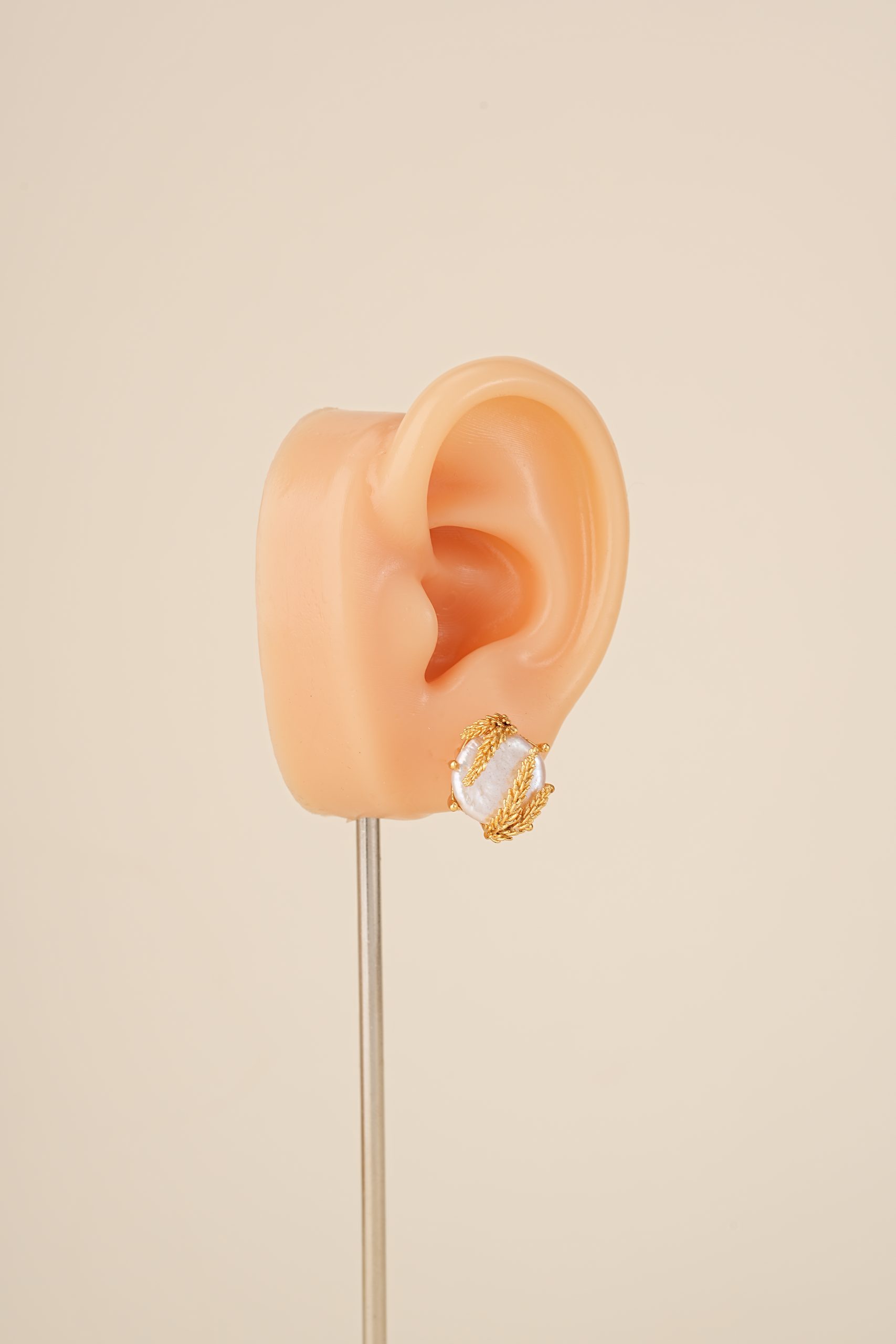 Wheat-wrapped baroque pearl stud earring on an ear display