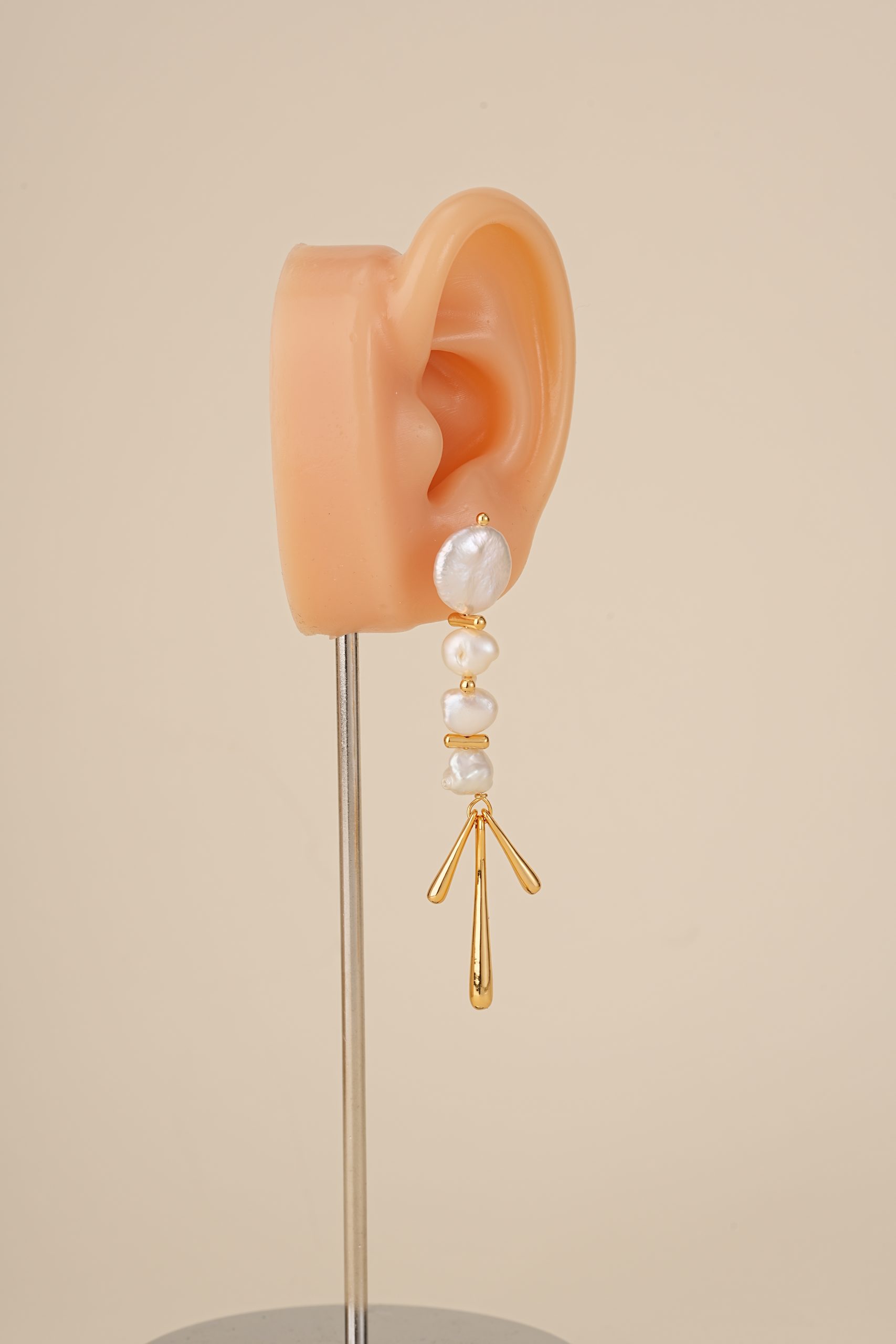 Gold-tone baroque pearl chandelier earring on an ear display