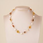 Amber-toned resin and pearl necklace displayed on a bust