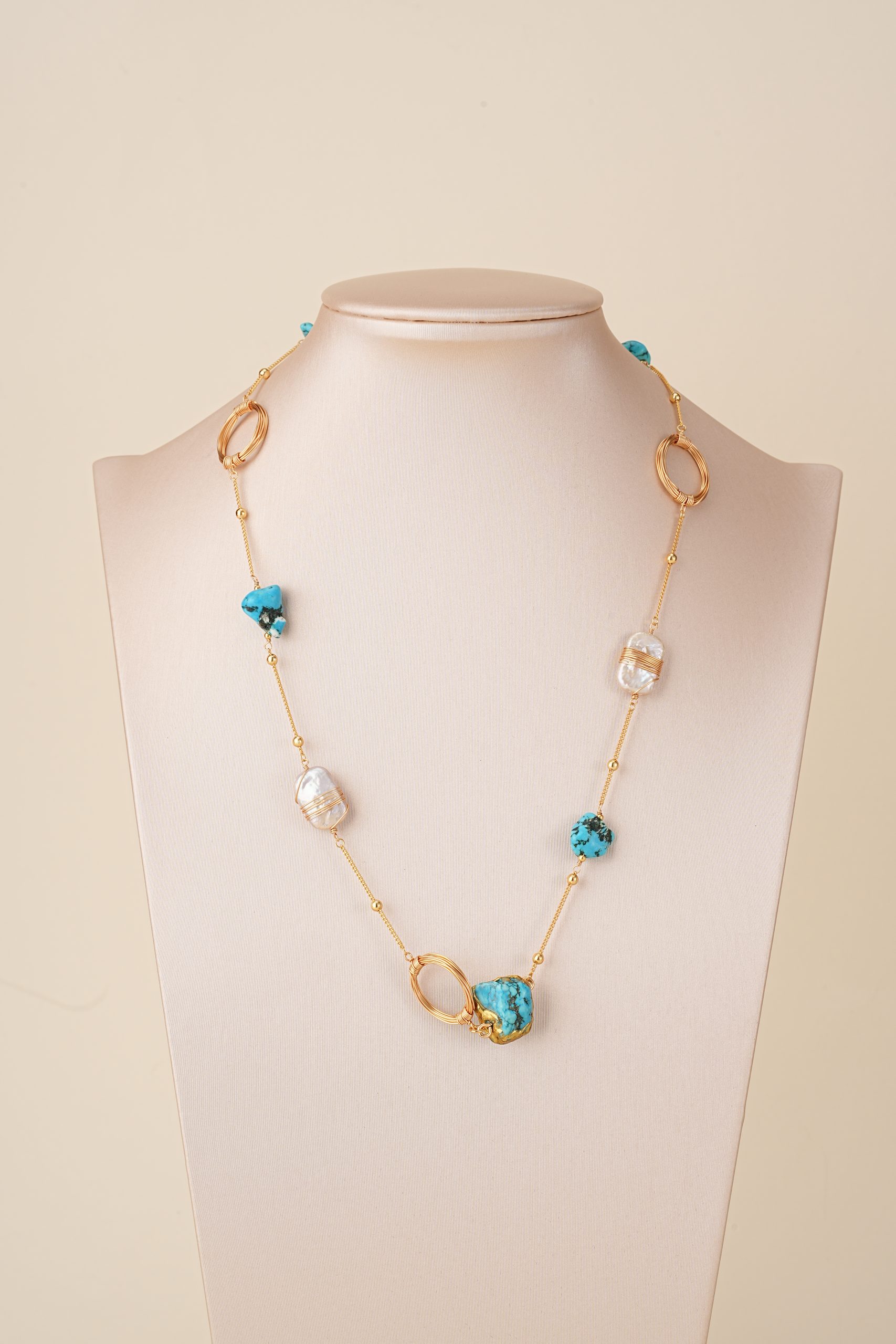 Turquoise and baroque pearl necklace displayed on a bust