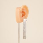 Silver-tone pearl tassel earring shown on an ear display