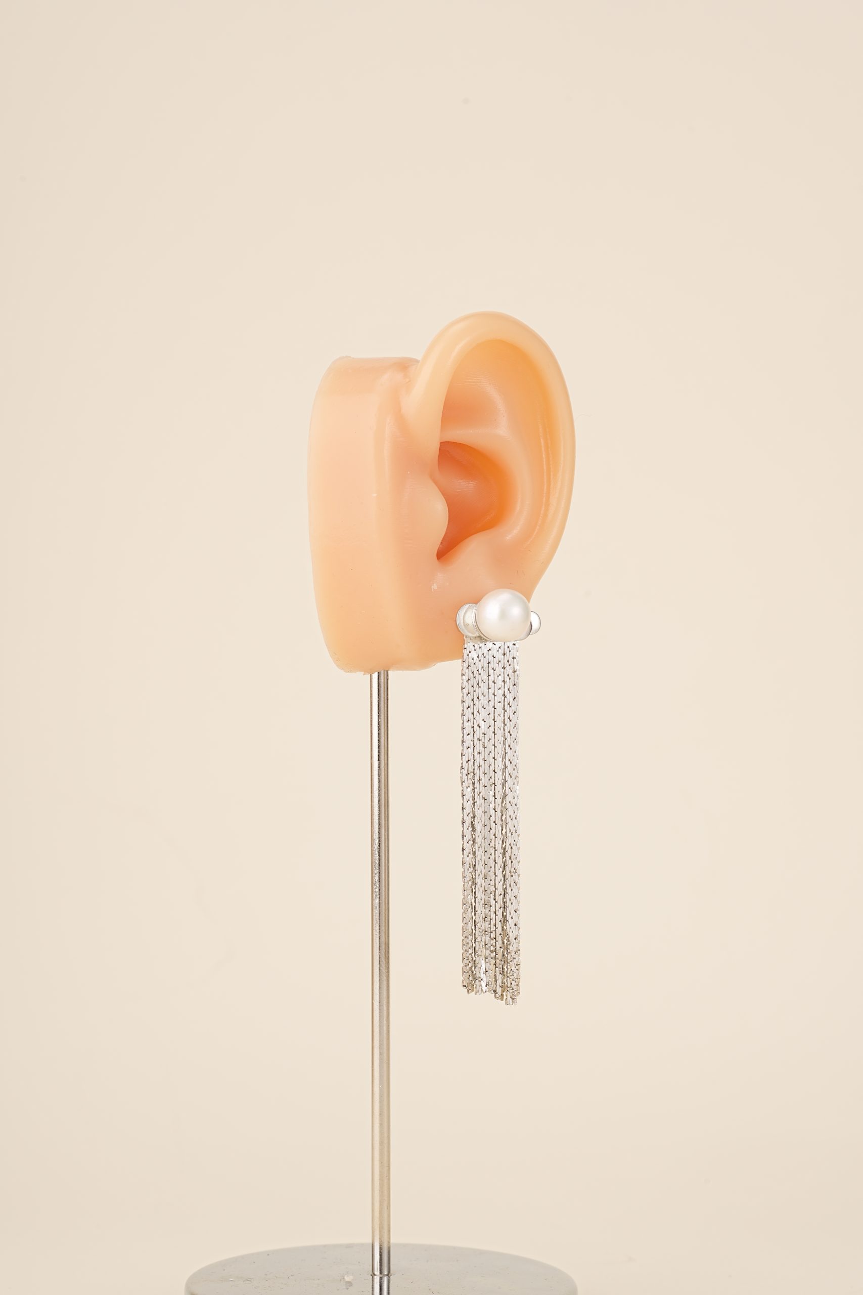 Silver-tone pearl tassel earring shown on an ear display