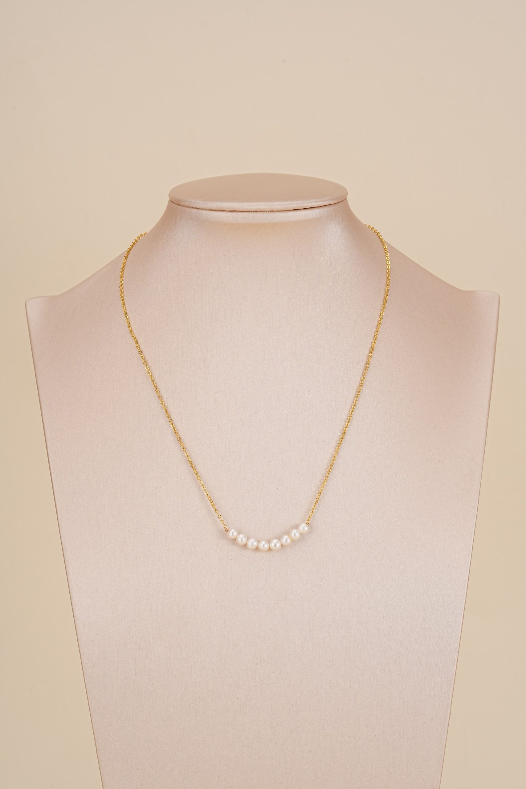 Eight-pearl gold-tone necklace displayed on a bust
