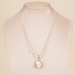 Pearl-accented necklace with white pendant displayed on a bust