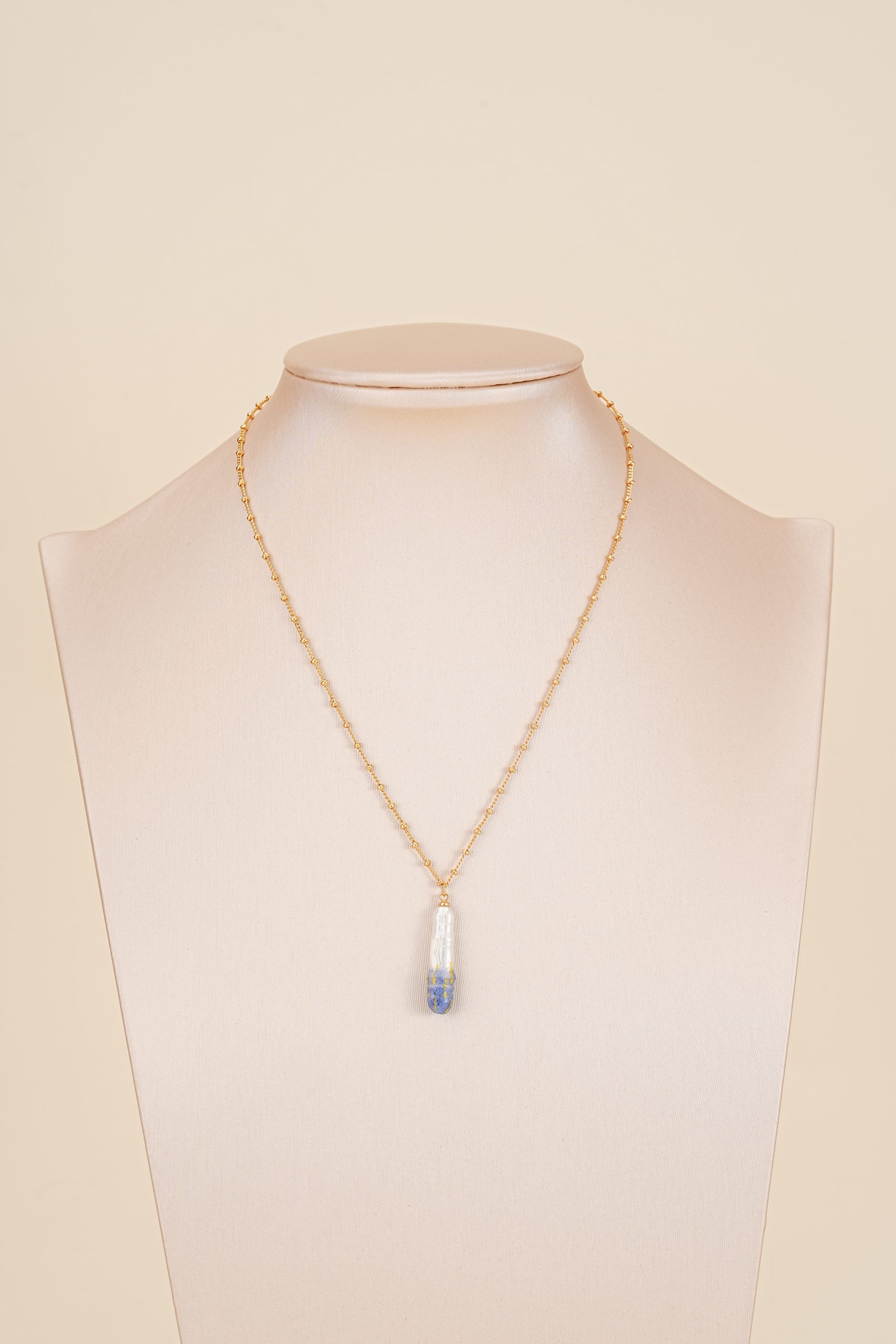 Painted pearl pendant necklace displayed on a bust