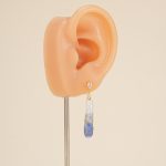 Painted pearl drop earring on an ear display