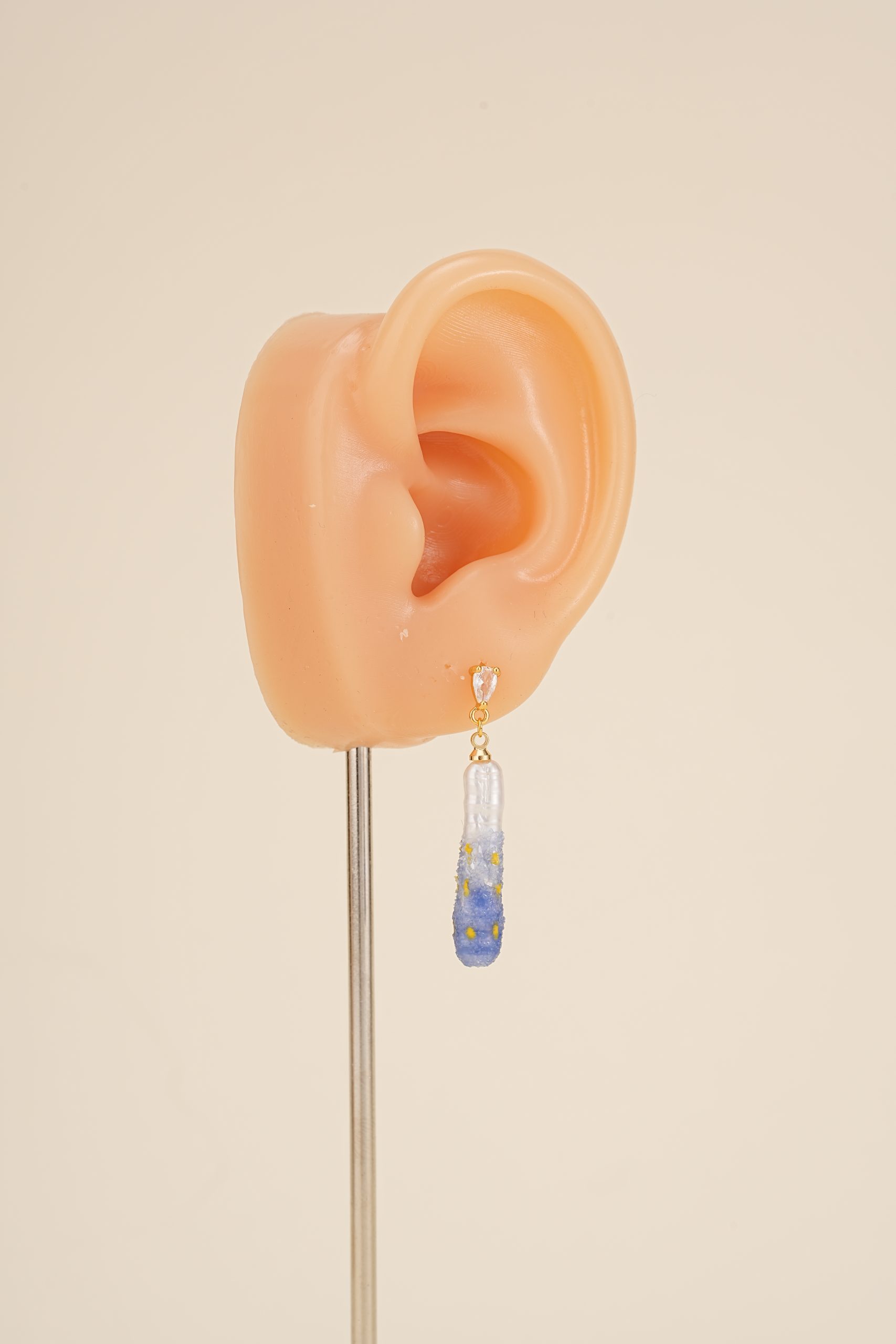 Painted pearl drop earring on an ear display