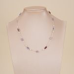 Purple gemstone and pearl necklace displayed on a jewelry bust