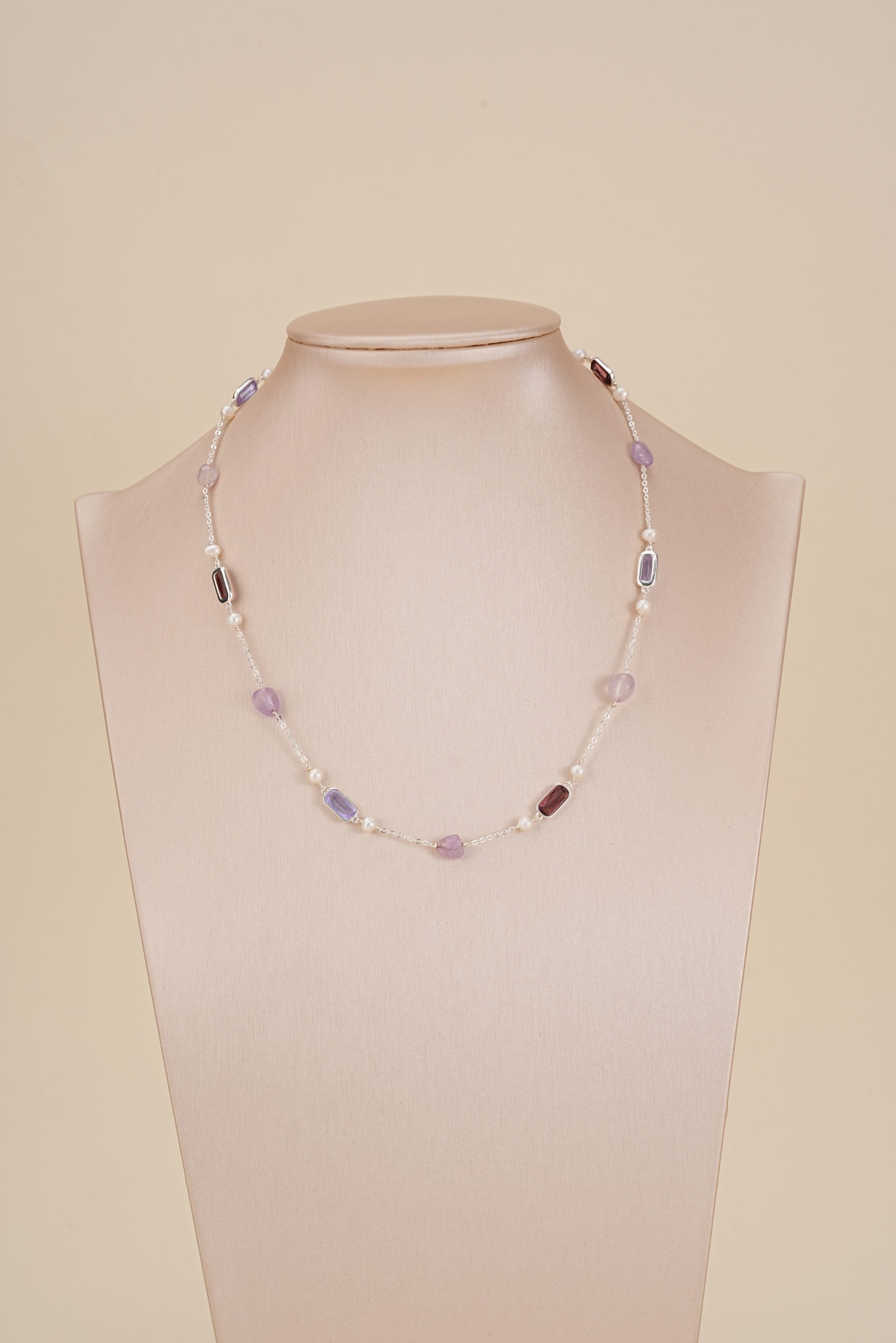 Purple gemstone and pearl necklace displayed on a jewelry bust