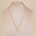 Long crystal pendant necklace displayed on a jewelry bust