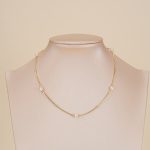 Short pearl-spaced necklace displayed on a jewelry bust