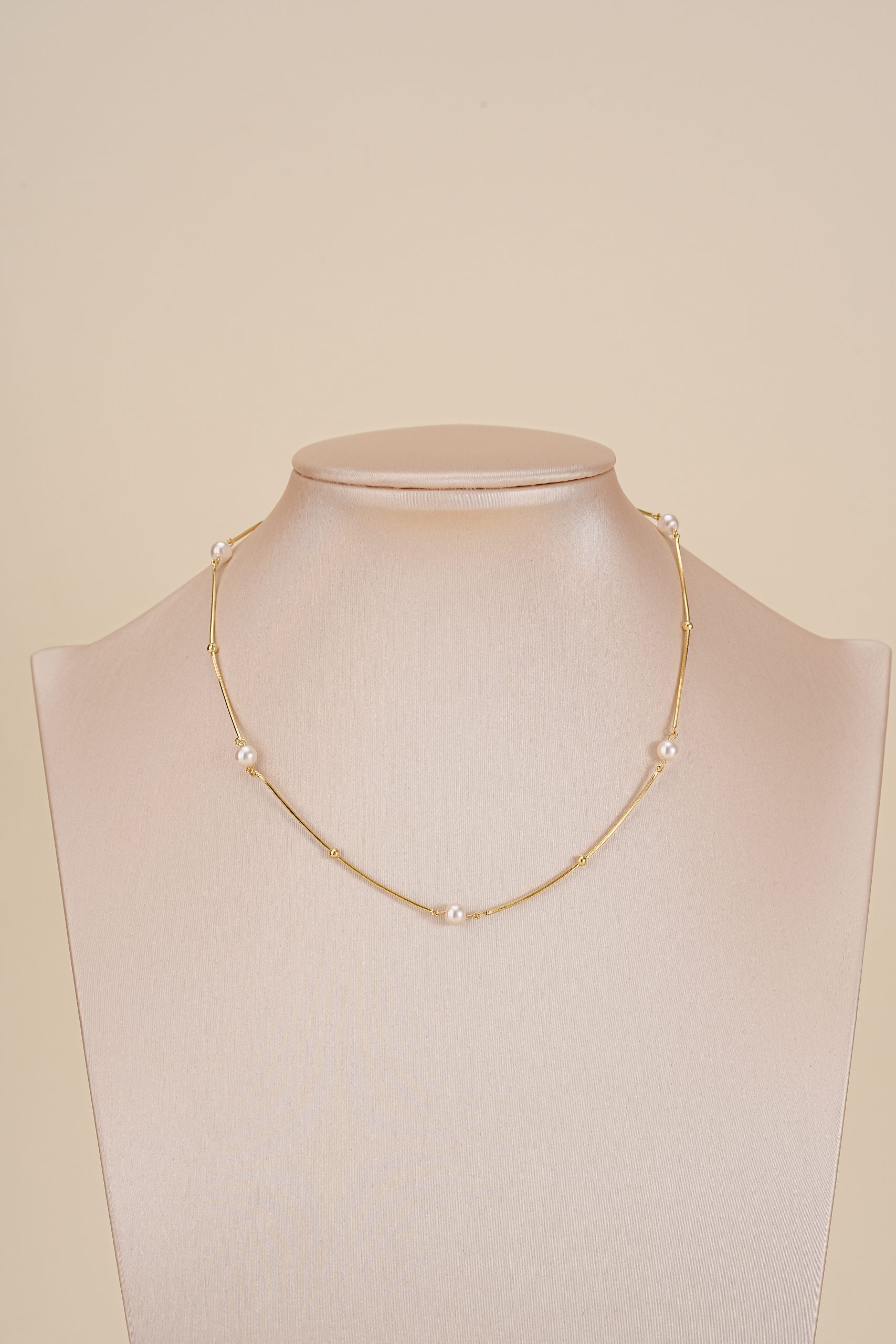 Short pearl-spaced necklace displayed on a jewelry bust