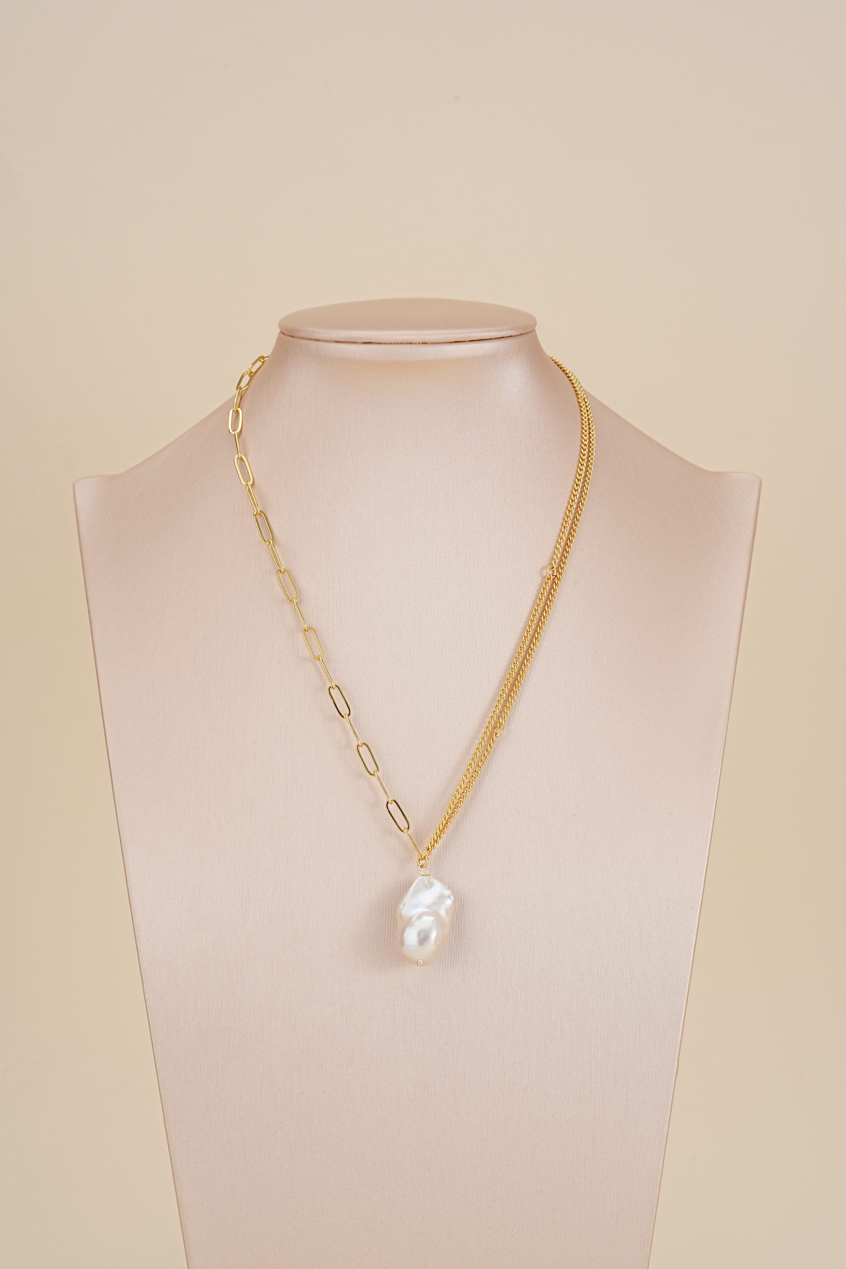 Asymmetric baroque pearl pendant necklace displayed on a jewelry bust