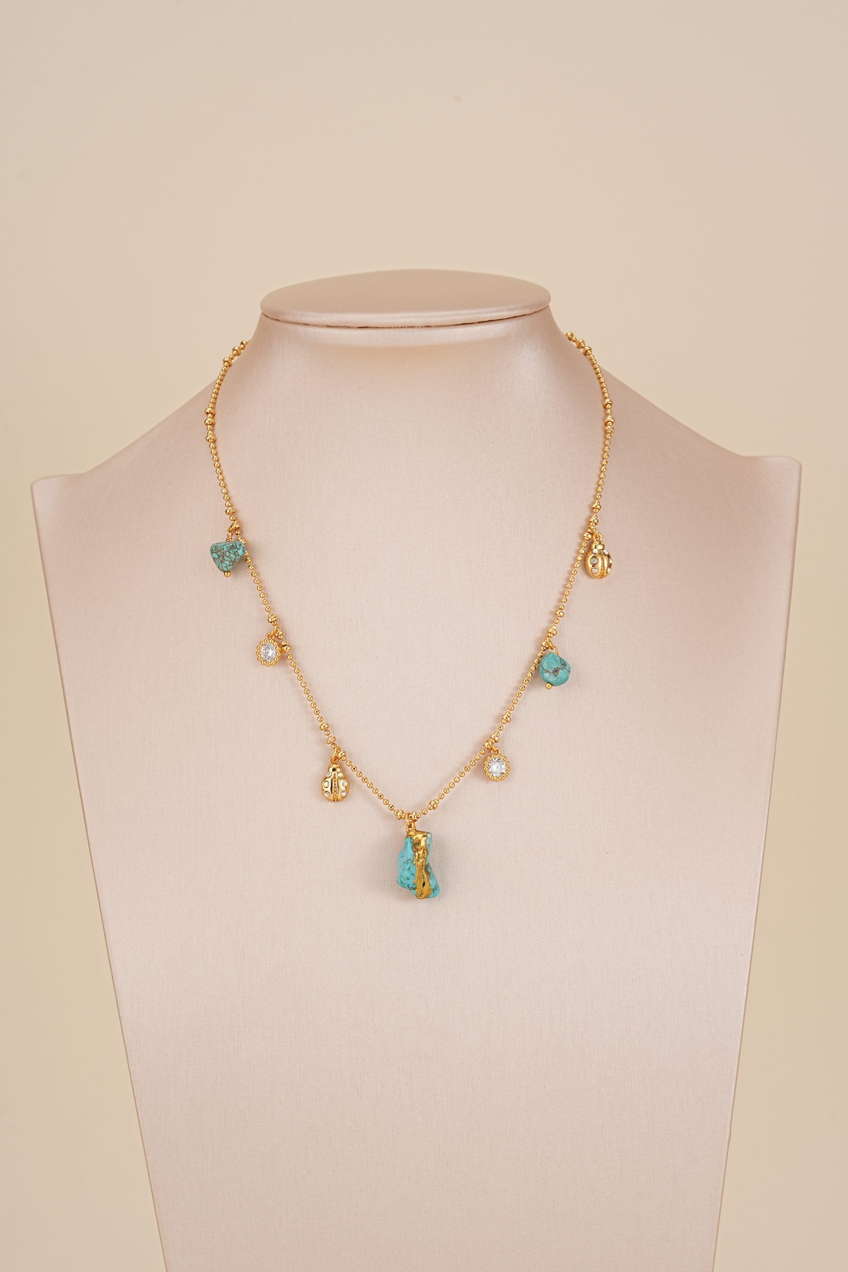 Turquoise charm bead chain necklace displayed on jewelry bust